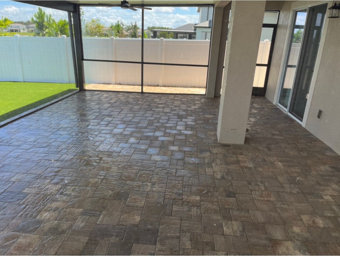 An empty room with a brick floor and a screened in porch.