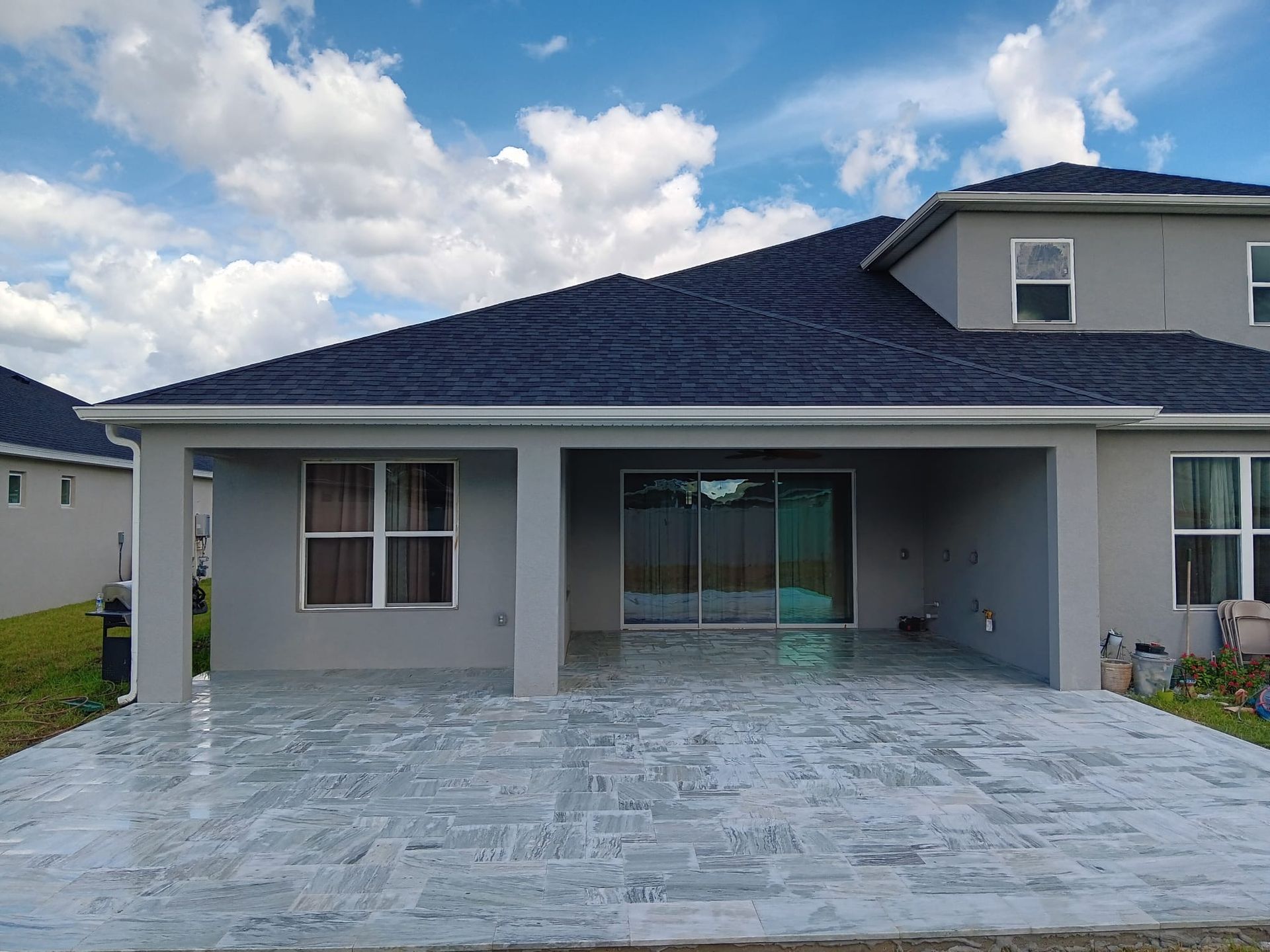 The back of a house with a covered patio and a blue roof.