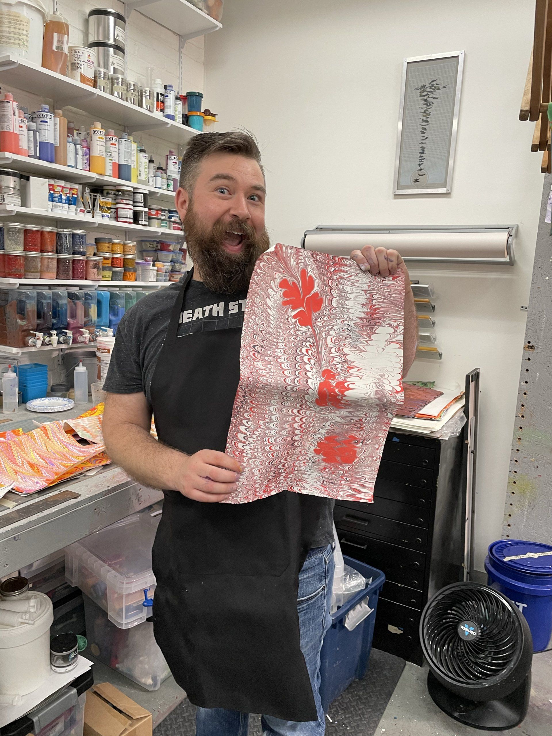 Enthusiastic man shows off his creation in the Paper Marbling Experience.