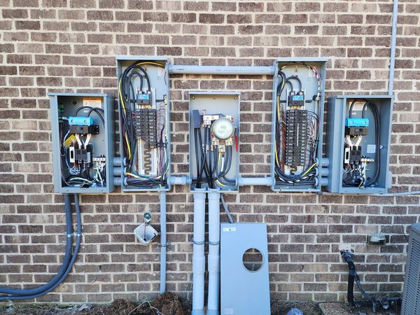 Electrical panels mounted on a brick wall, with conduits and wiring.