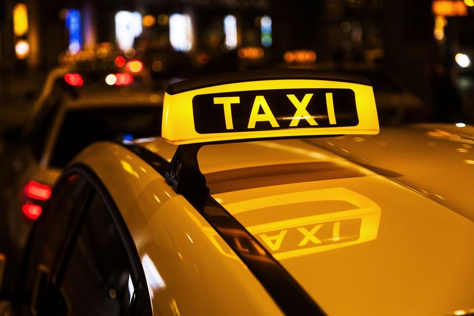 Insegna gialla sul tetto di un taxi che brilla di notte su una strada cittadina