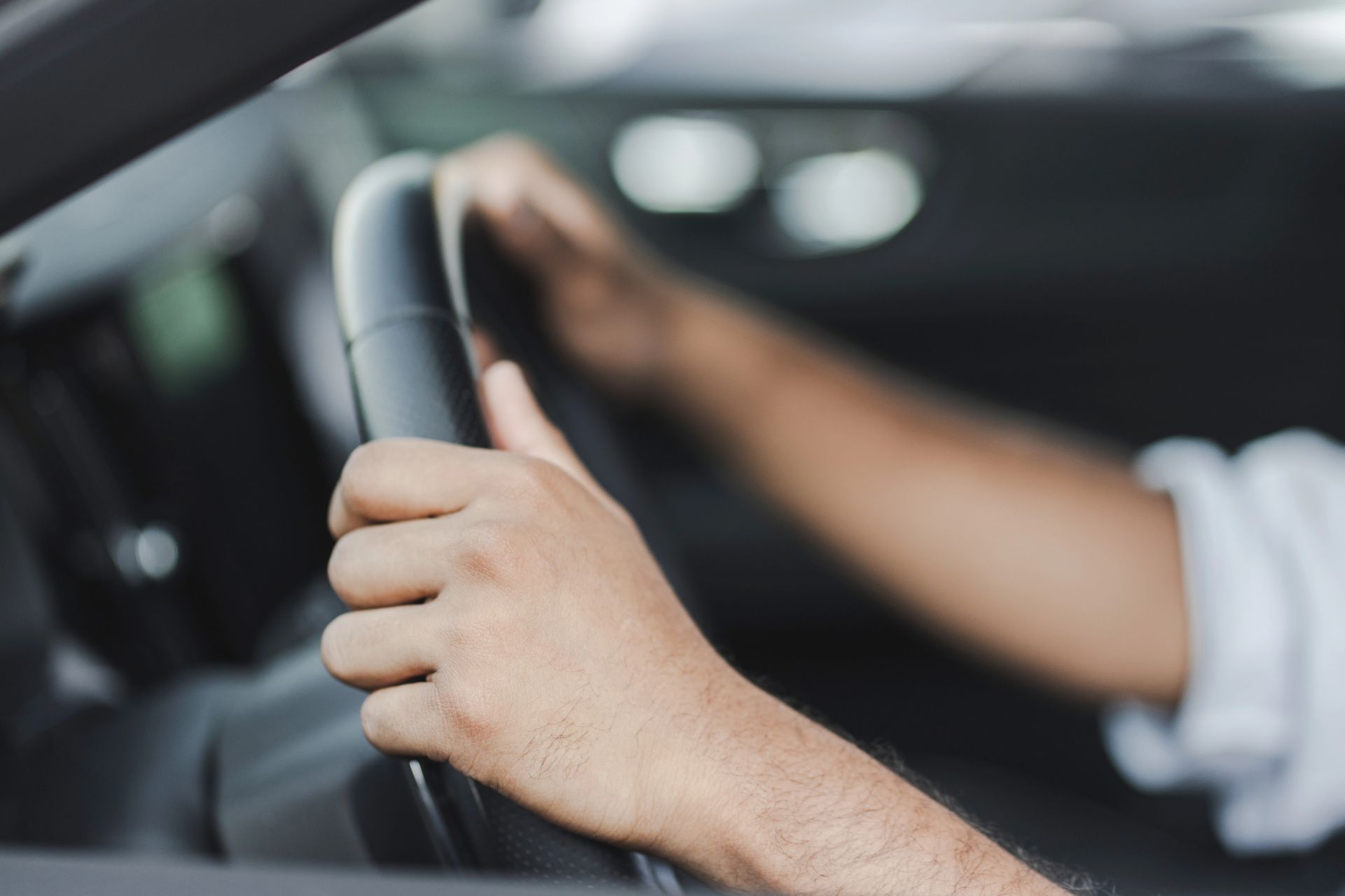 Mani che impugnano il volante di un'auto durante la guida.