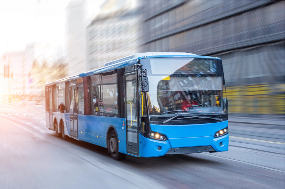 Autobus urbano blu che percorre una strada cittadina sfocata