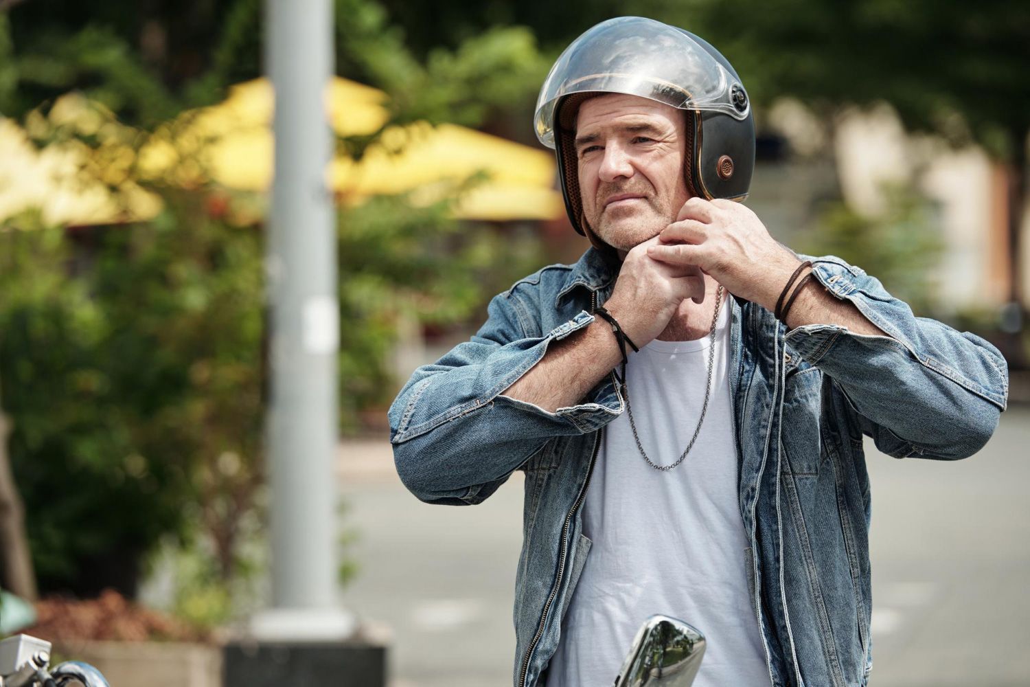 A man wearing a helmet is standing on a street.