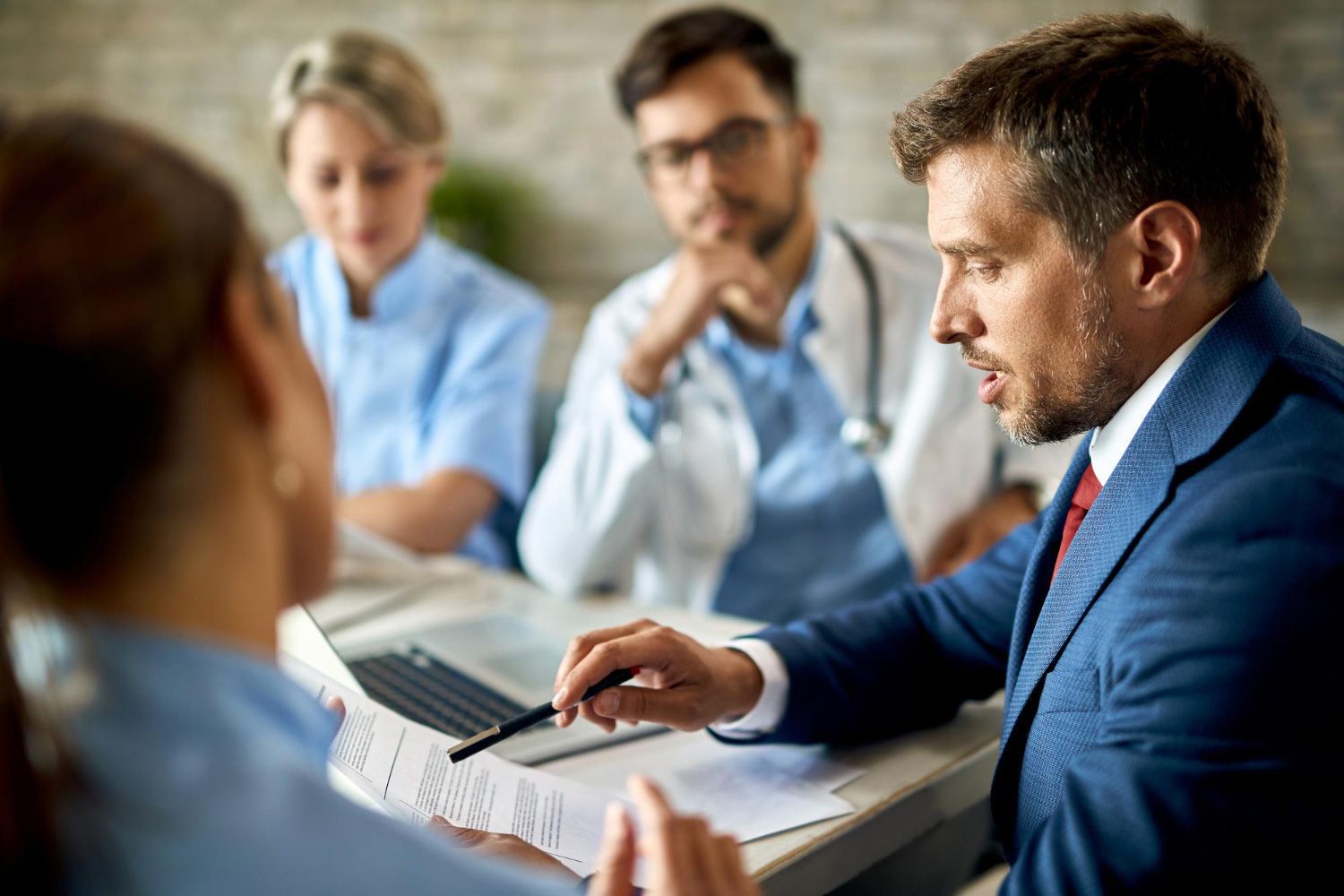 A group of doctors and nurses are having a meeting with a man in a suit.