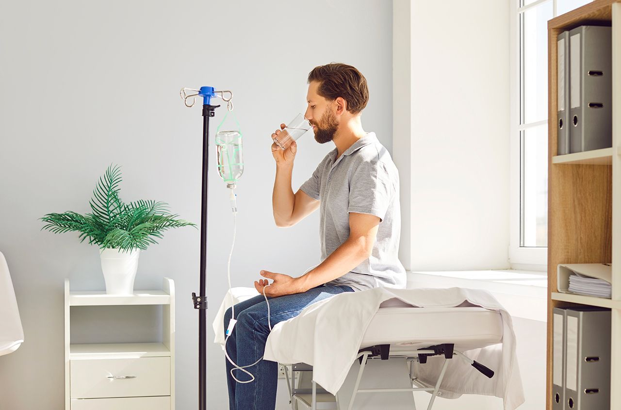 Man seated on a treatment table using a nebulizer in a bright home room