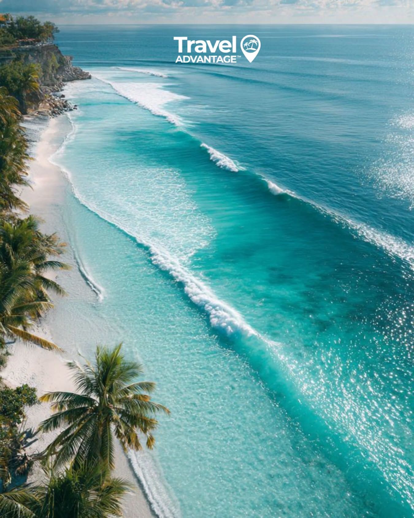 Aerial view of turquoise ocean waves along a tropical coastline with palm trees and a sandy beach