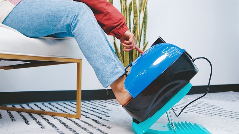 A person is sitting on a chair with their foot on a machine.