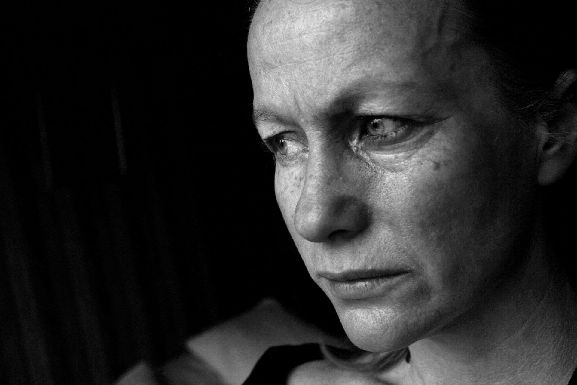A close up of a woman 's face with a tear coming out of her eye.