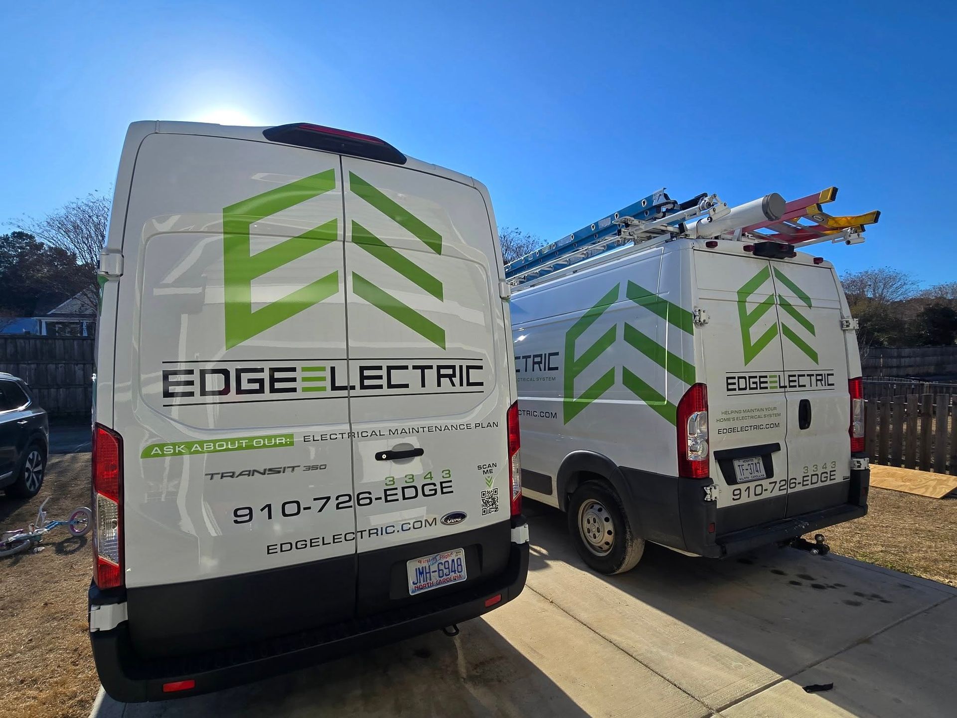 Two white Edge Electric vans with green logos parked outside on a sunny day.