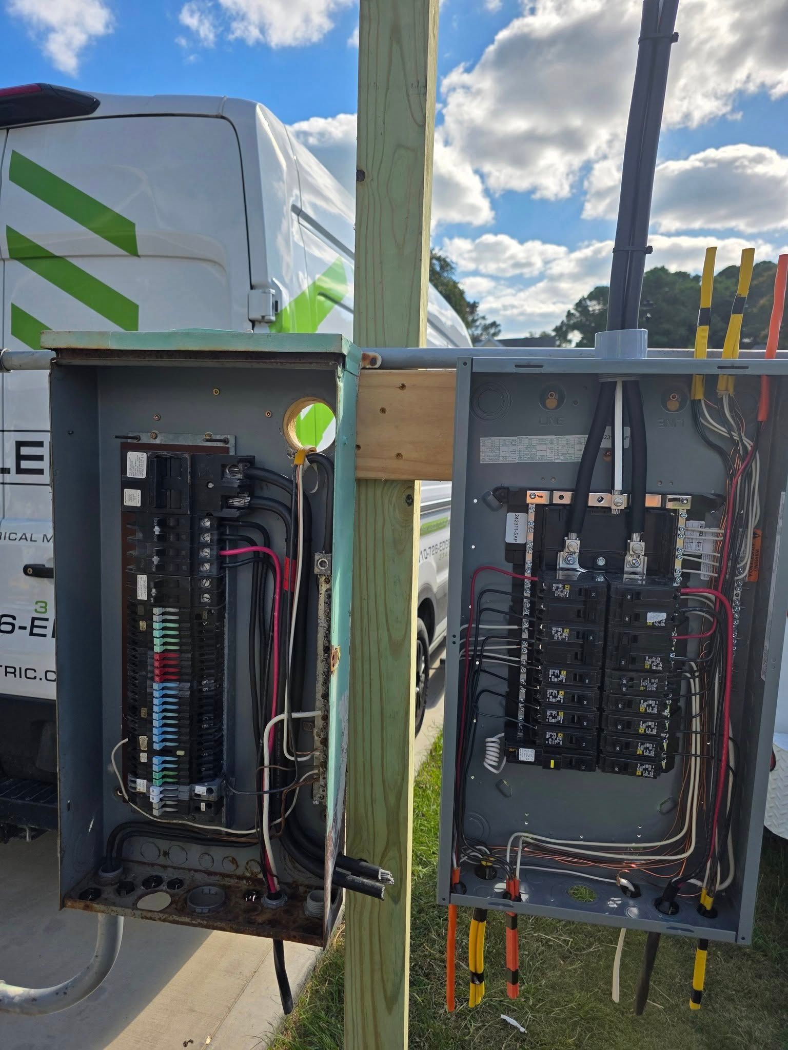 Two open electrical panels mounted on a utility pole. Wires and breakers are visible. 