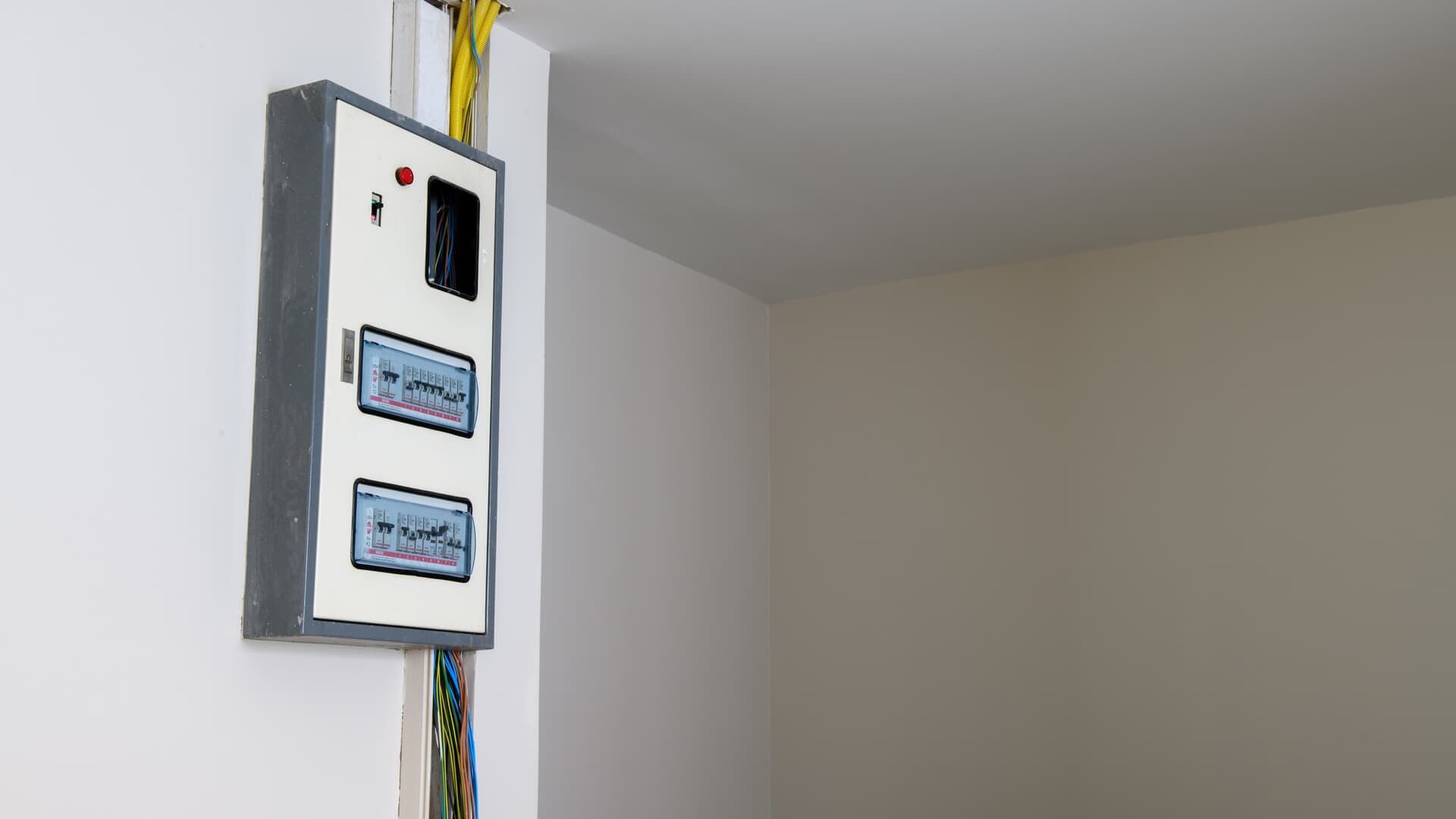 Electrical panel mounted on a white wall, with wiring.