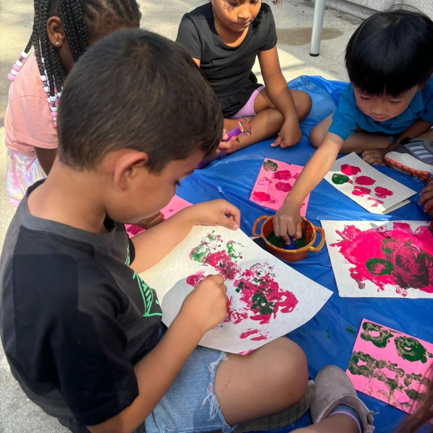 A group of children are sitting around a table painting