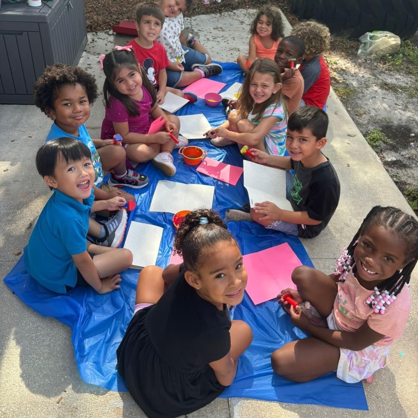 A group of children are sitting on a blue blanket