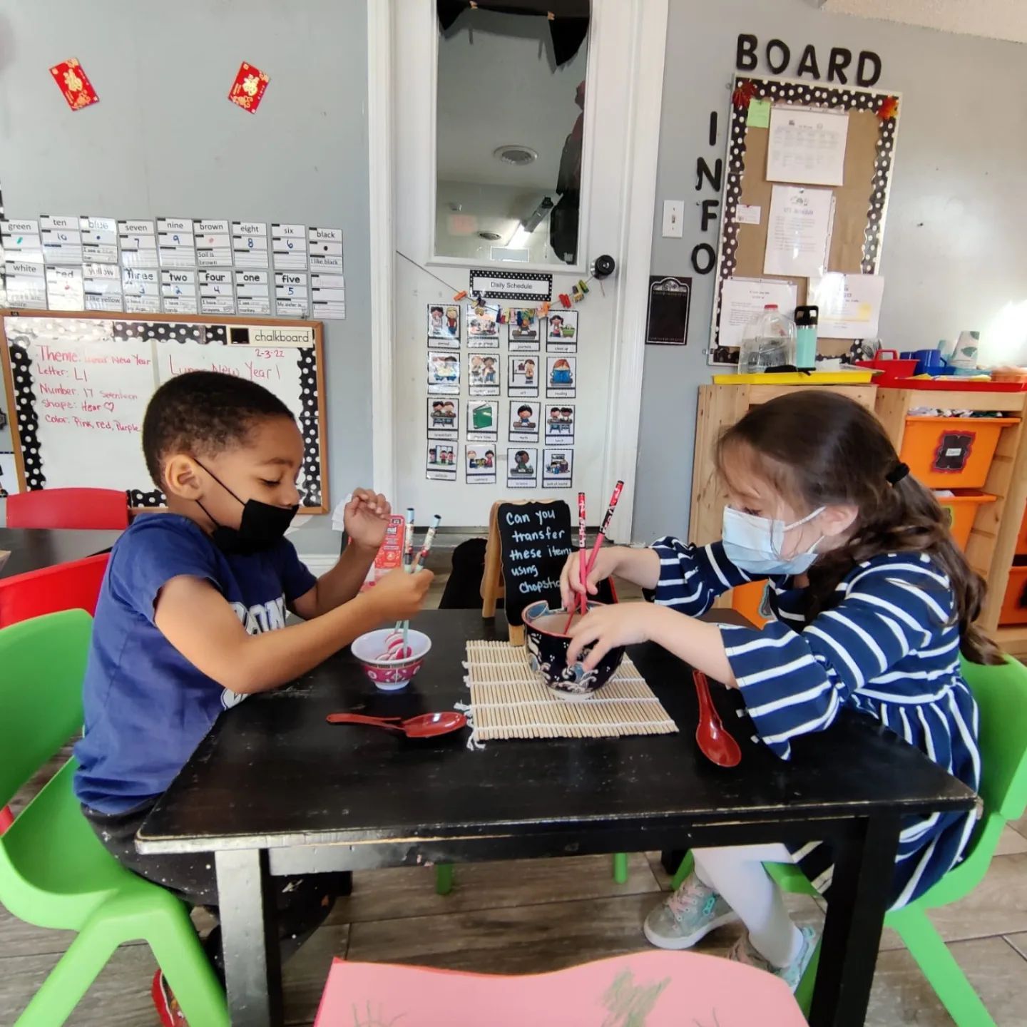A boy and a girl are sitting at a table in front of a sign that says board
