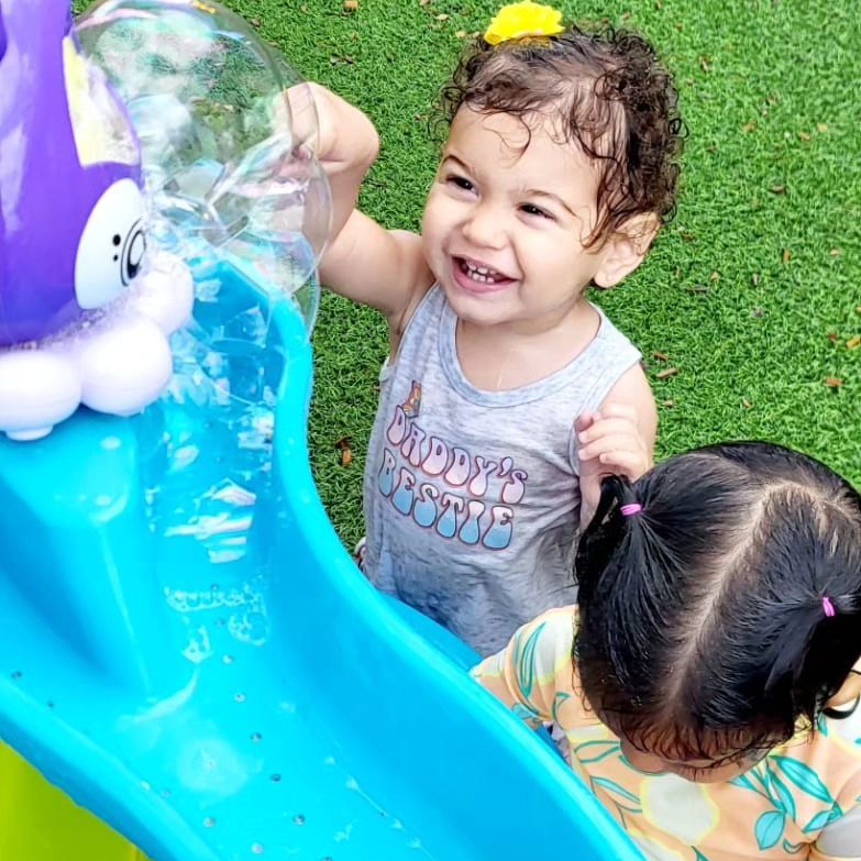 Two little girls are playing on a water slide.