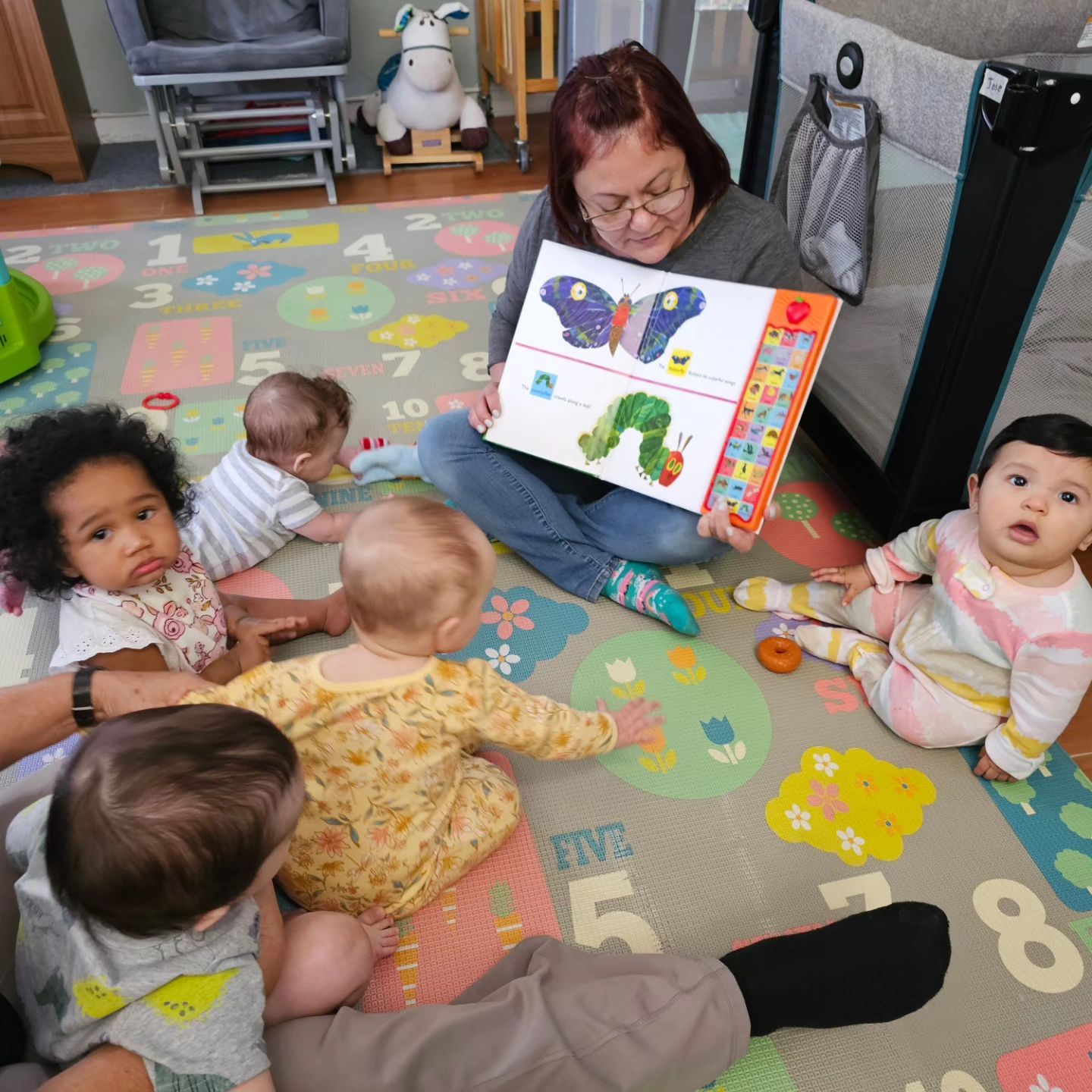 A woman is reading a book to a group of babies.