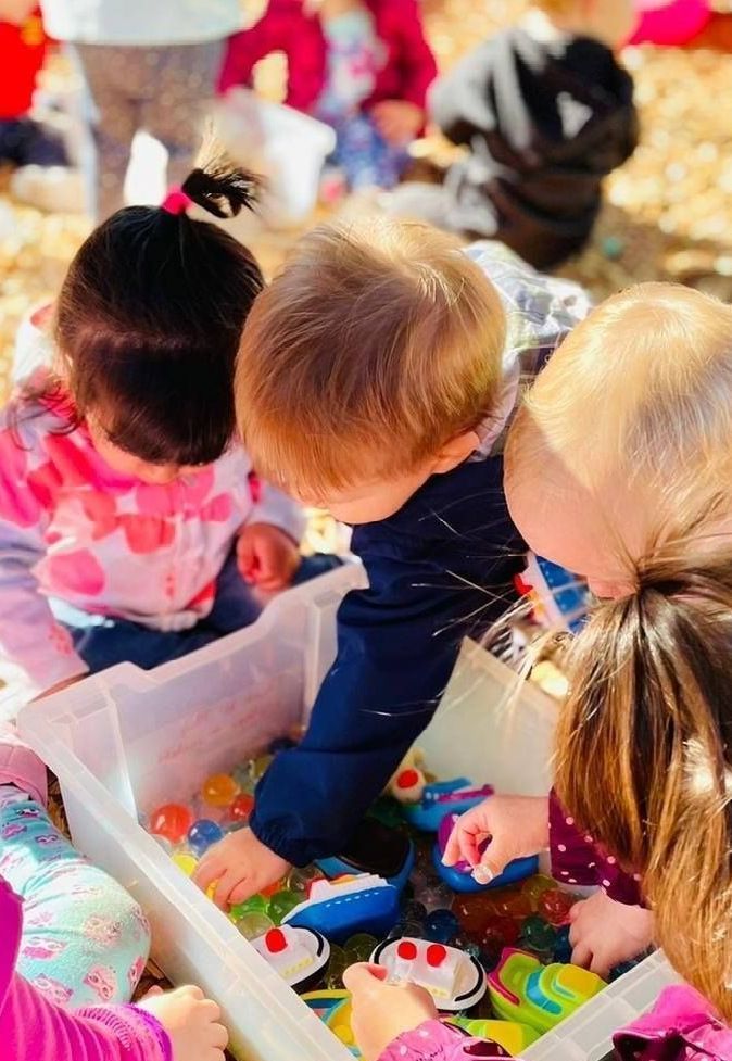 A group of children are playing with toys in a bin.