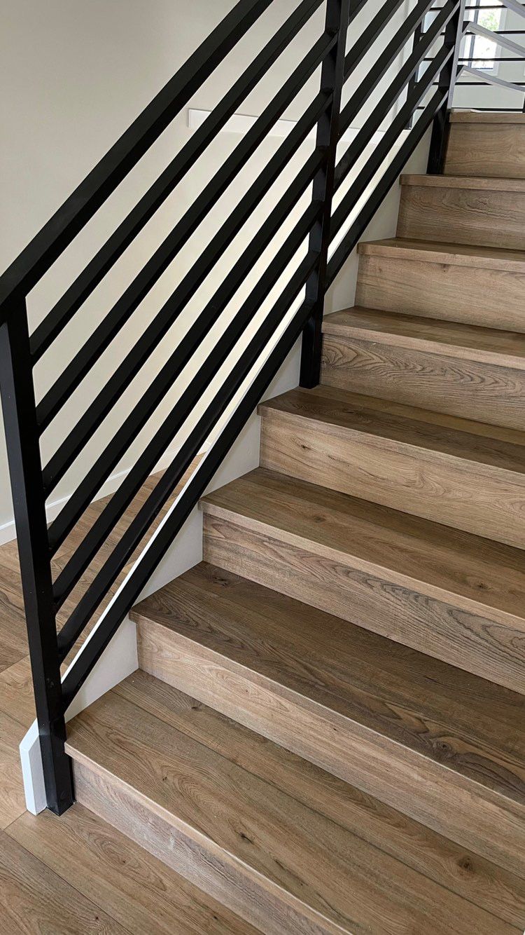 A staircase with wooden steps and a black railing.