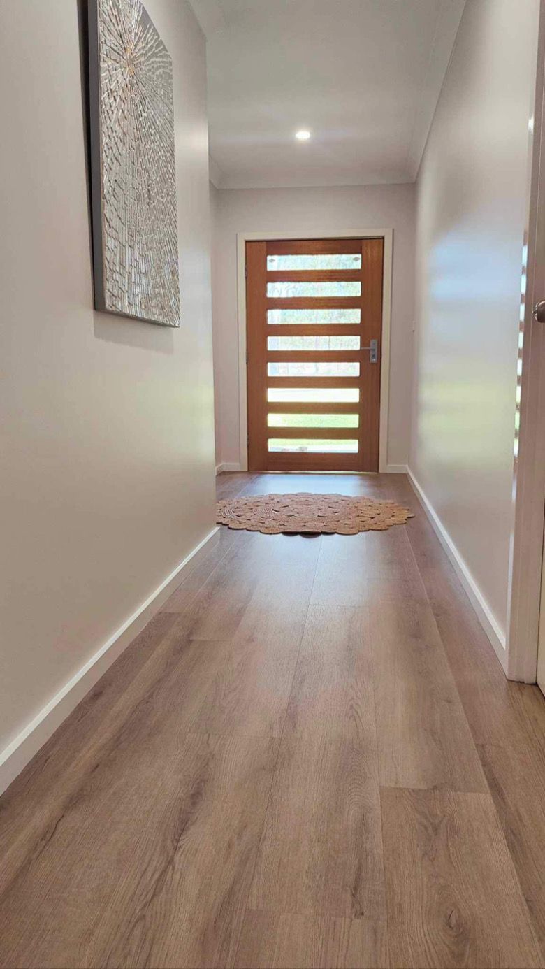 A hallway with a wooden floor and a wooden door in a house.