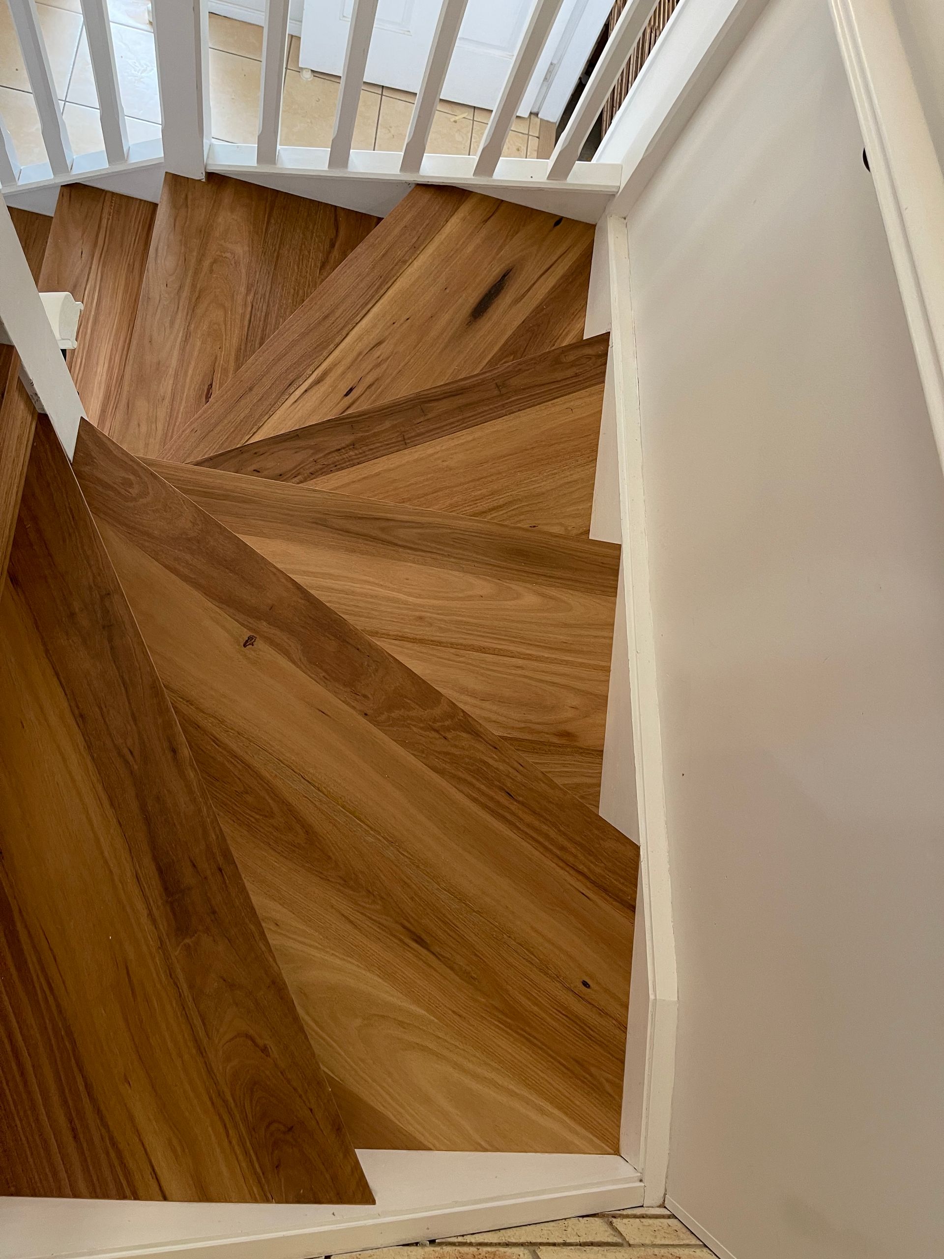 Wooden staircase with angled design; white trim and railing on walls.