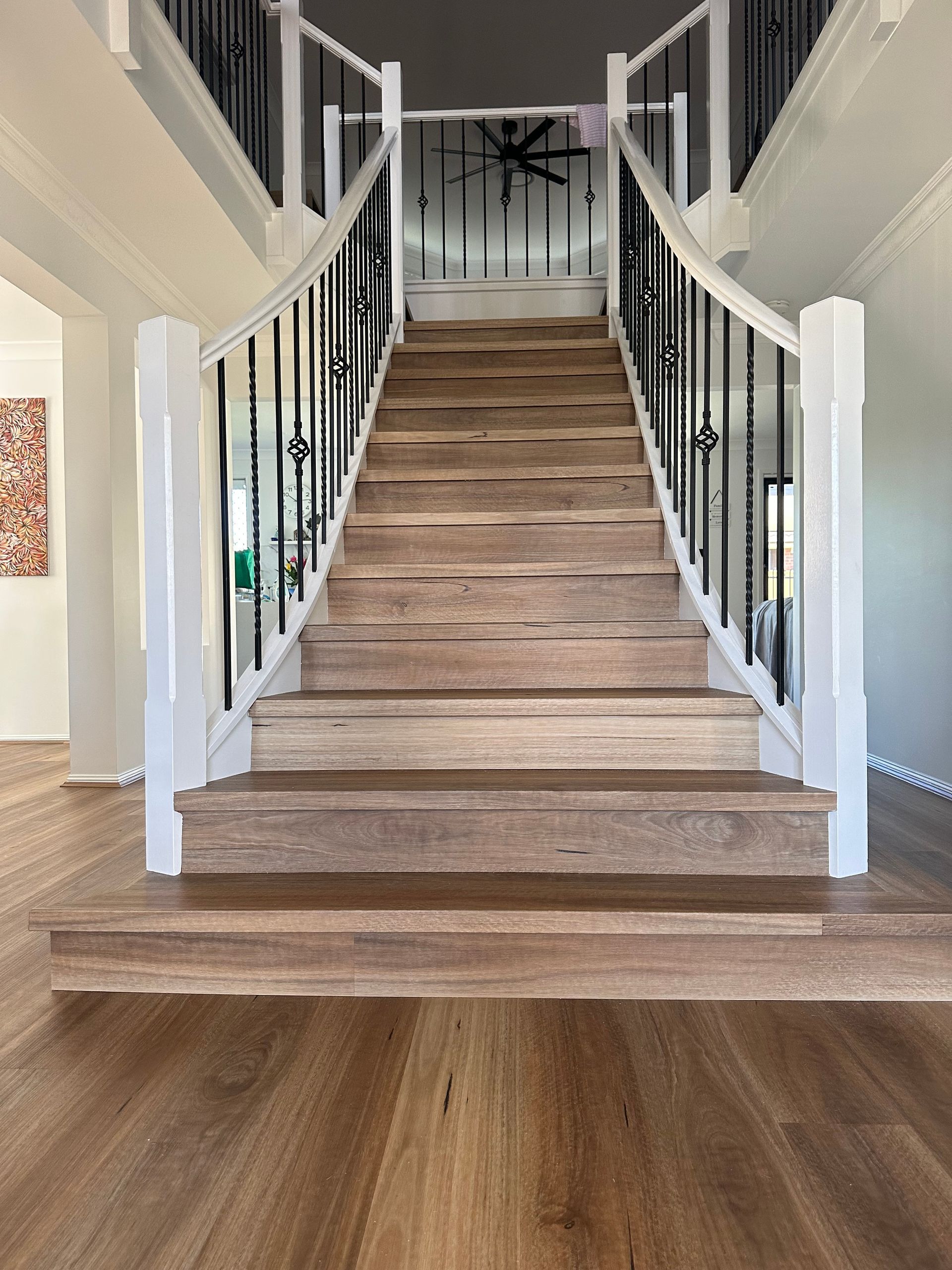 A wooden staircase with a white railing in a house.