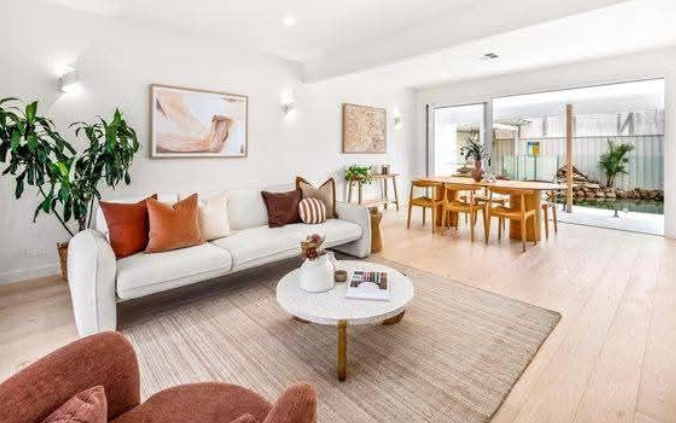 Living room with hardwood floors, large TV, potted plant, and sliding door to a backyard.