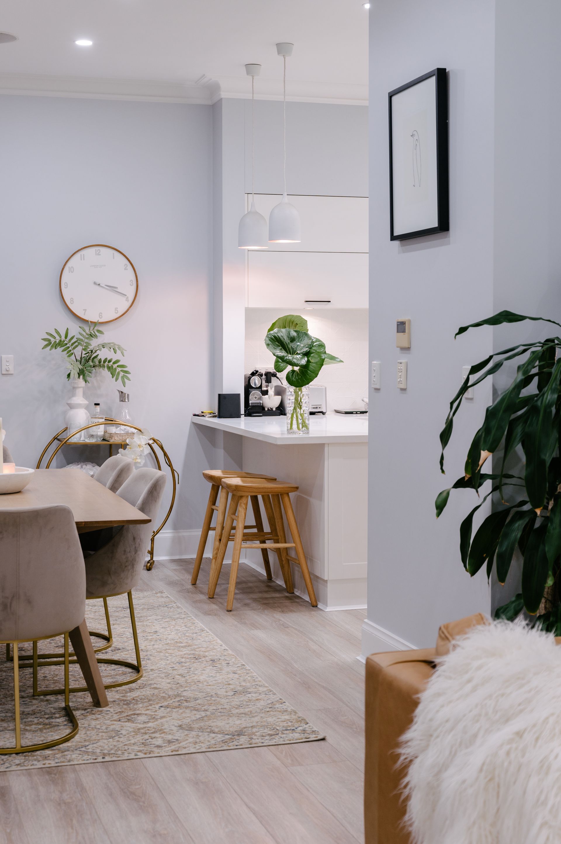 A living room with a table and chairs and a clock on the wall.