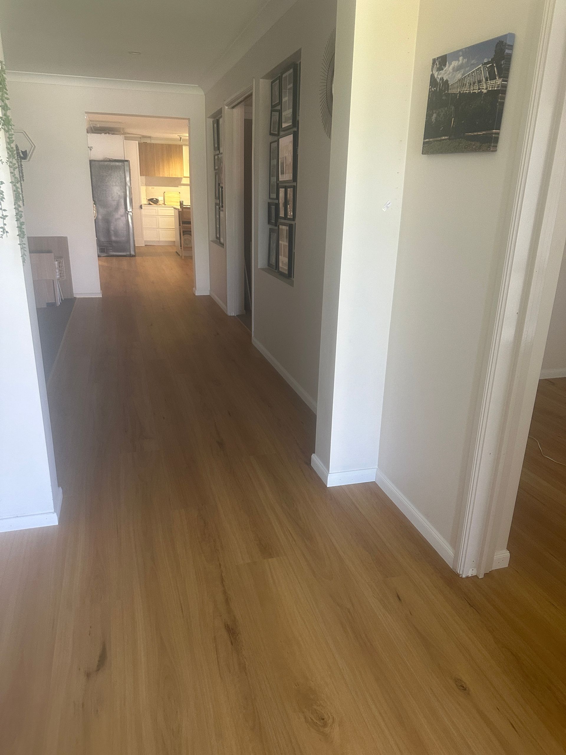 A hallway in a house with hardwood floors and white walls.