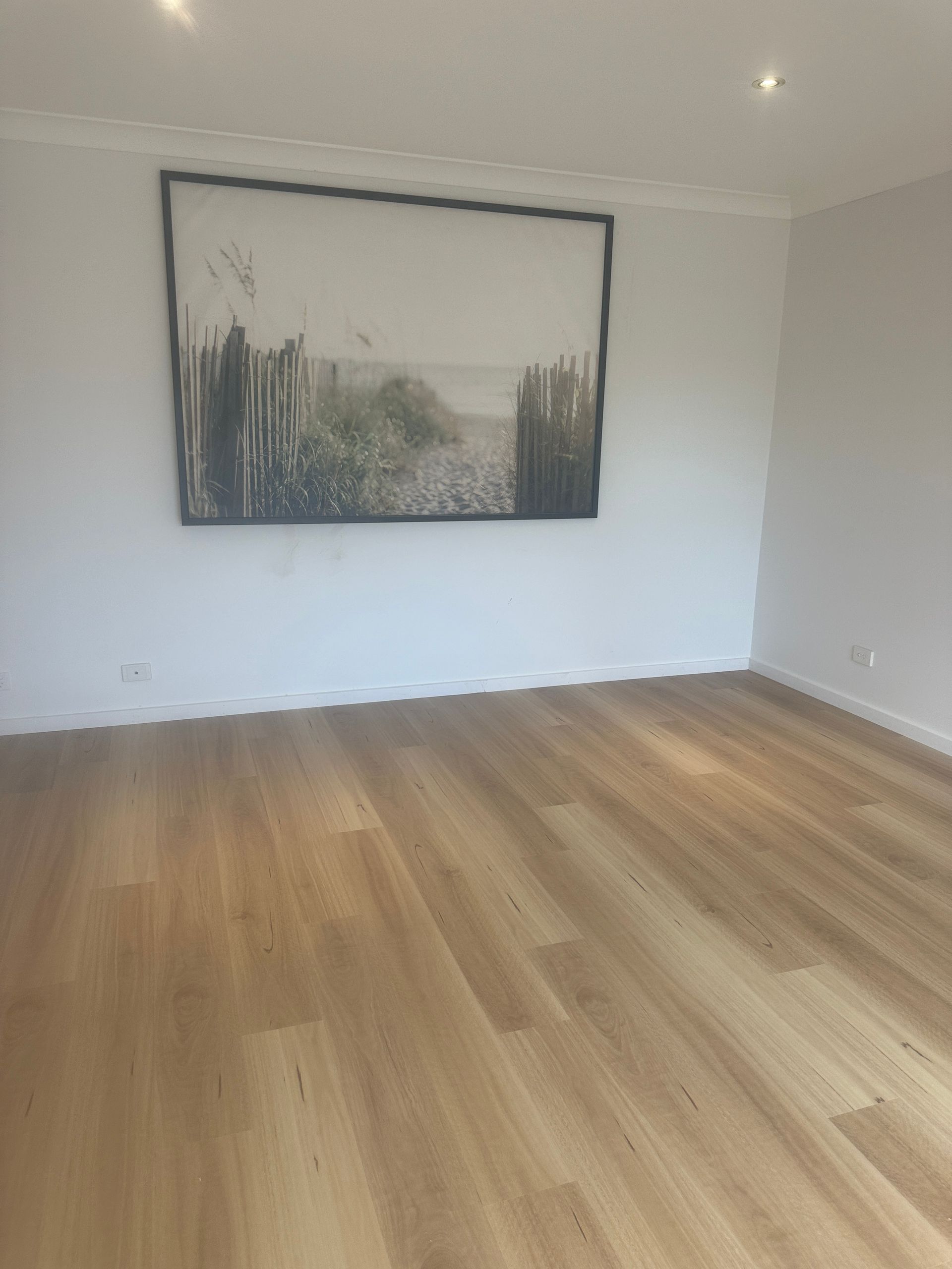 A living room with hardwood floors and a large painting on the wall.