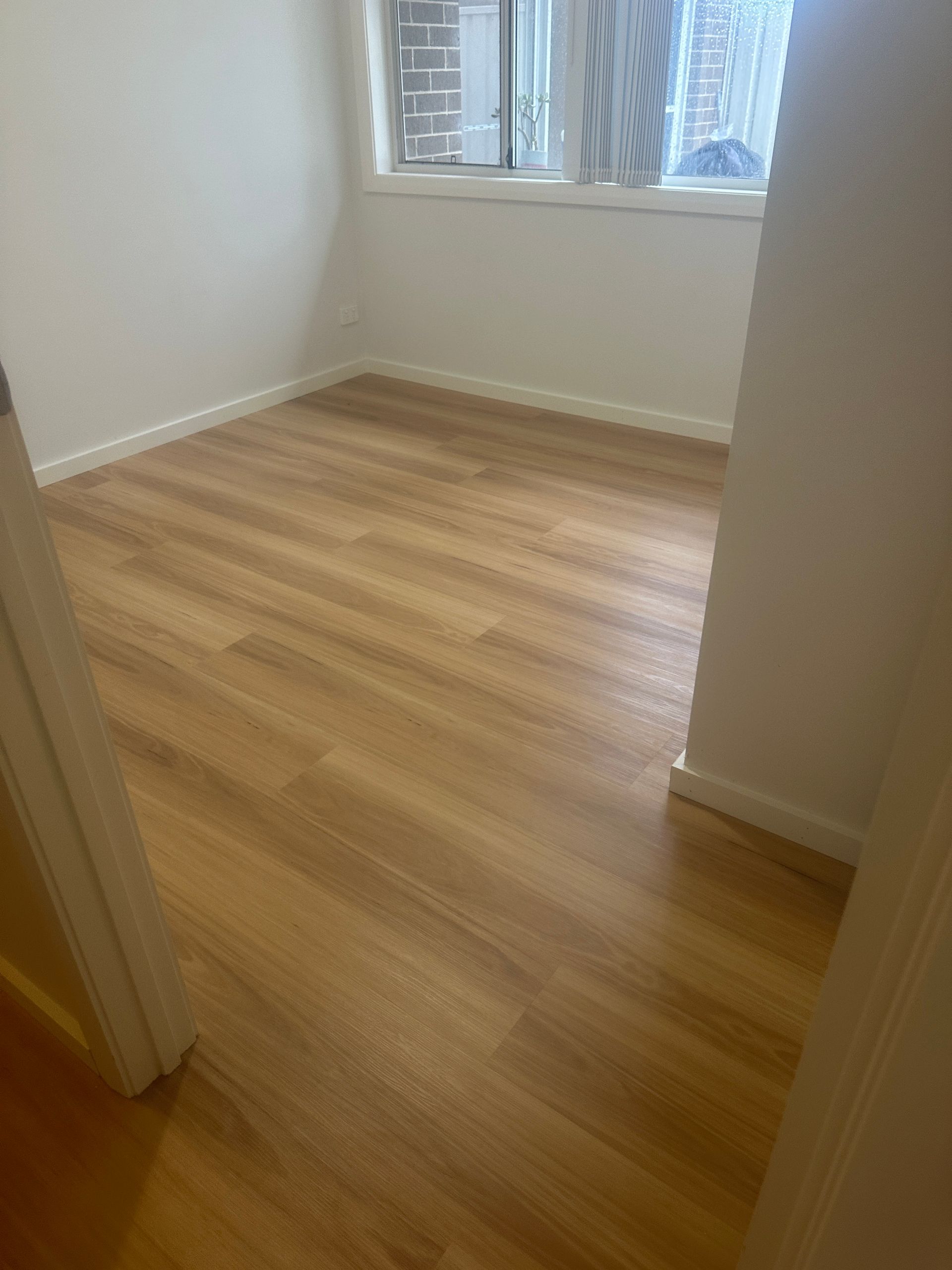 A room with a wooden floor and a window.