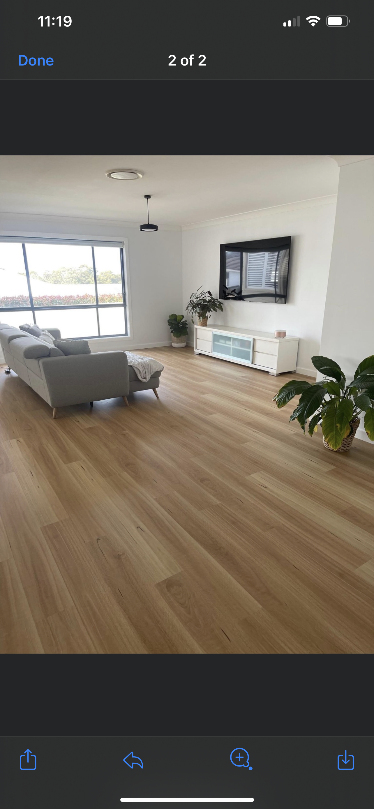 A living room with hardwood floors , a couch , and a television.