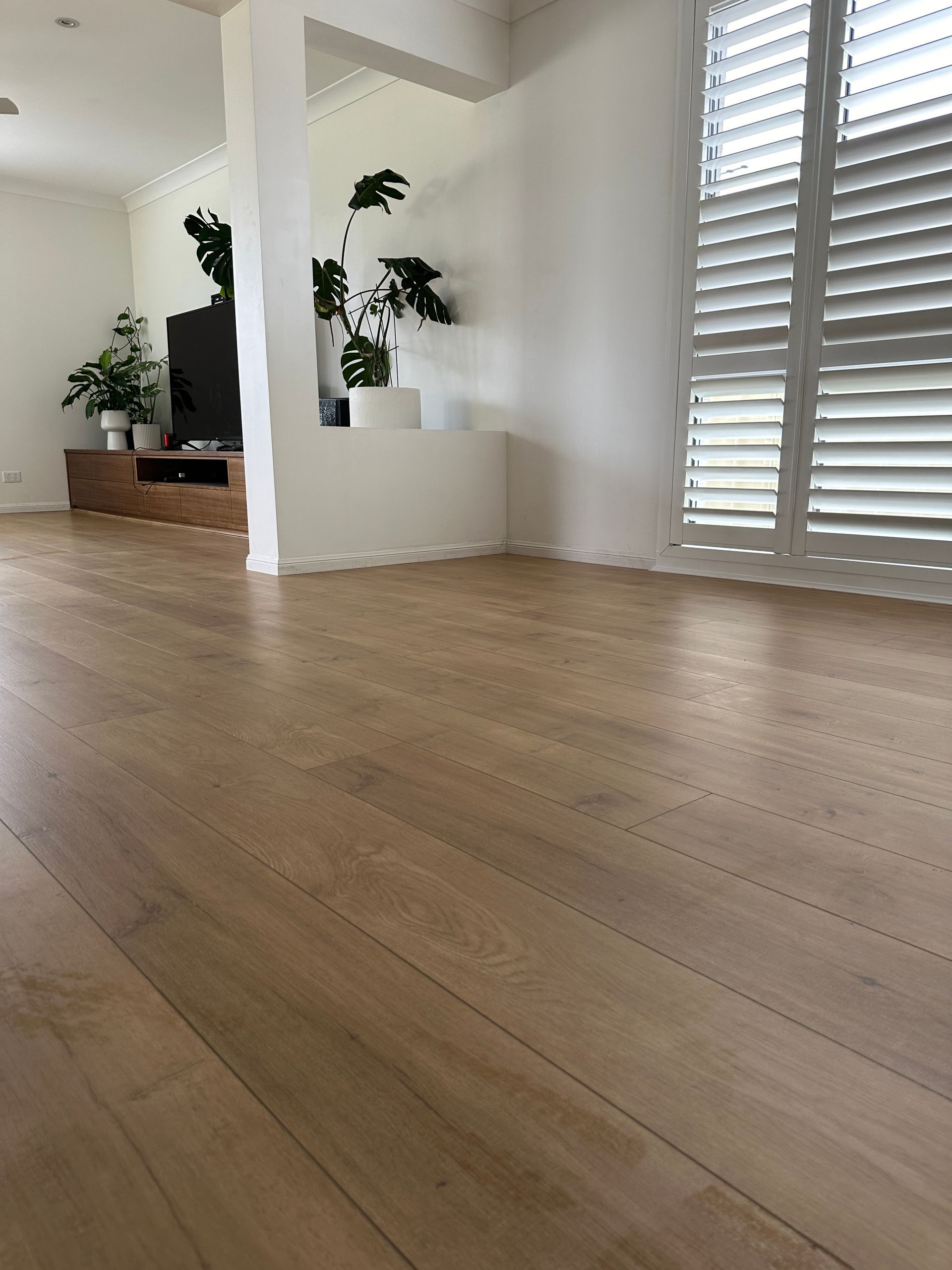 A living room with a wooden floor and white shutters.