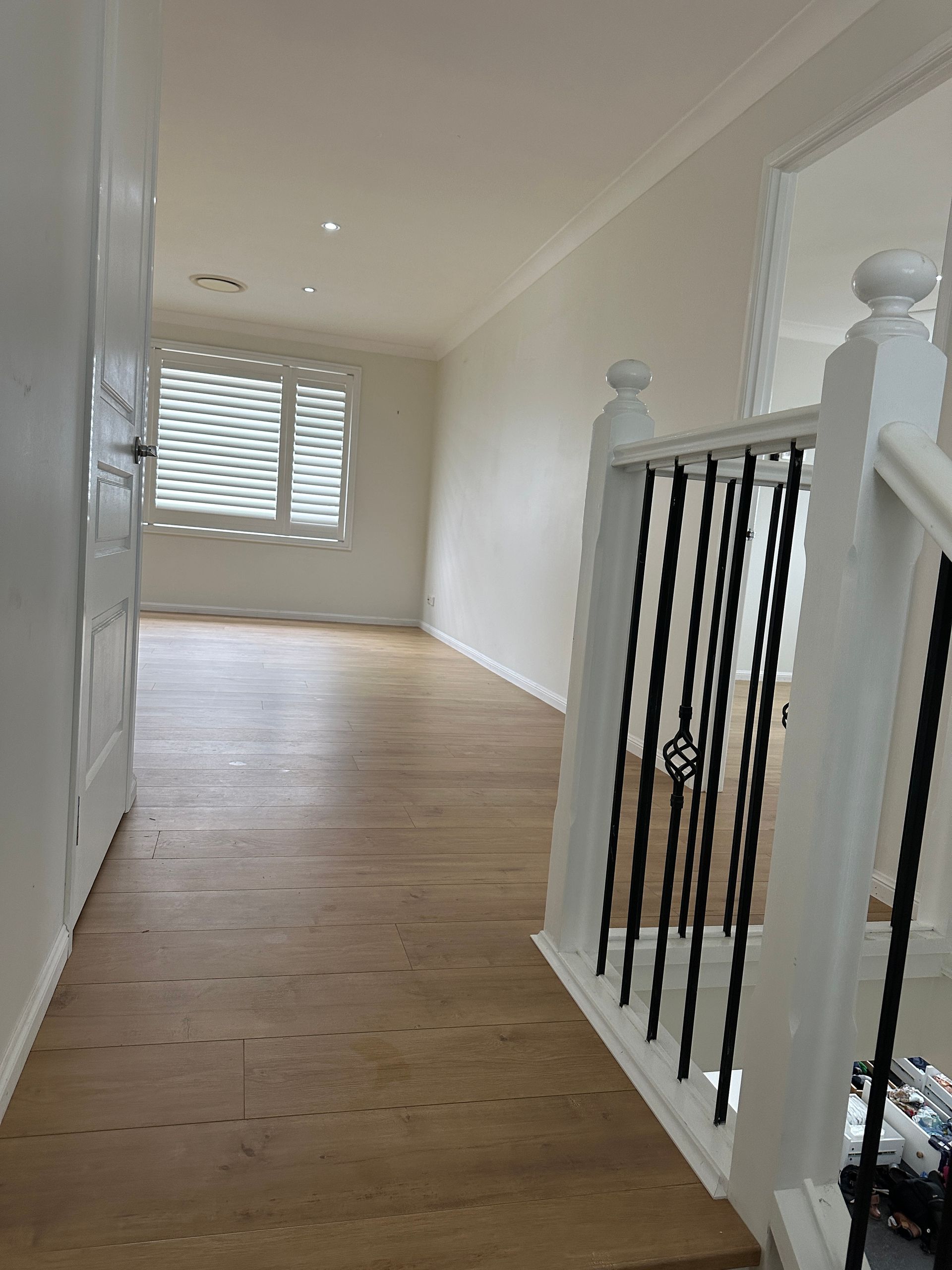 A hallway with wooden floors and stairs in a house.