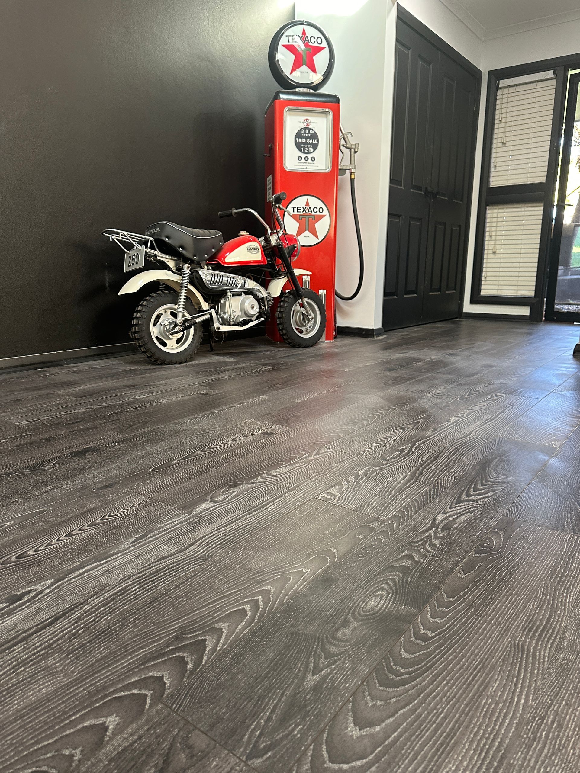 A motorcycle is parked next to a gas pump in a room.