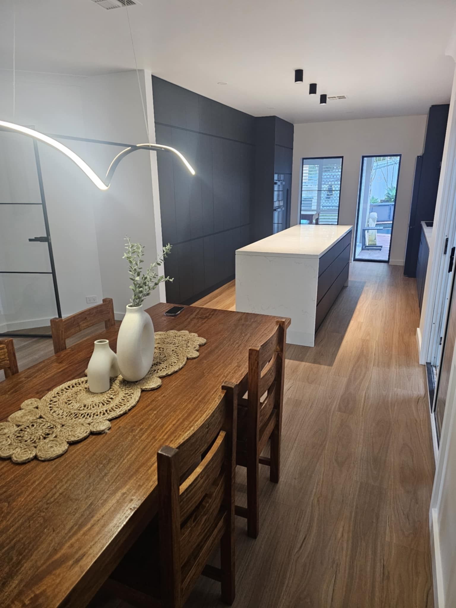 A dining room with a wooden table and chairs and a large island in the middle.