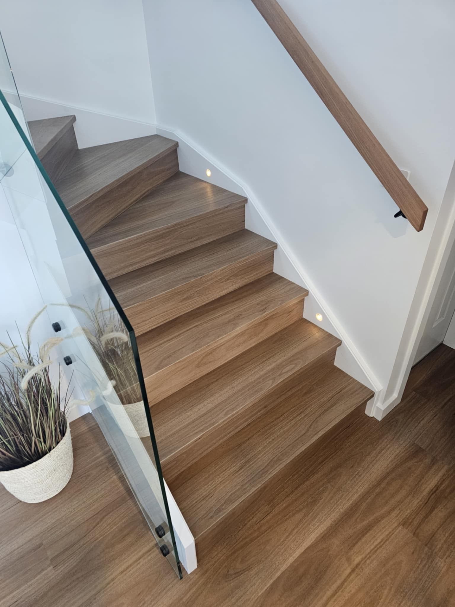 A wooden staircase with a glass railing in a house.