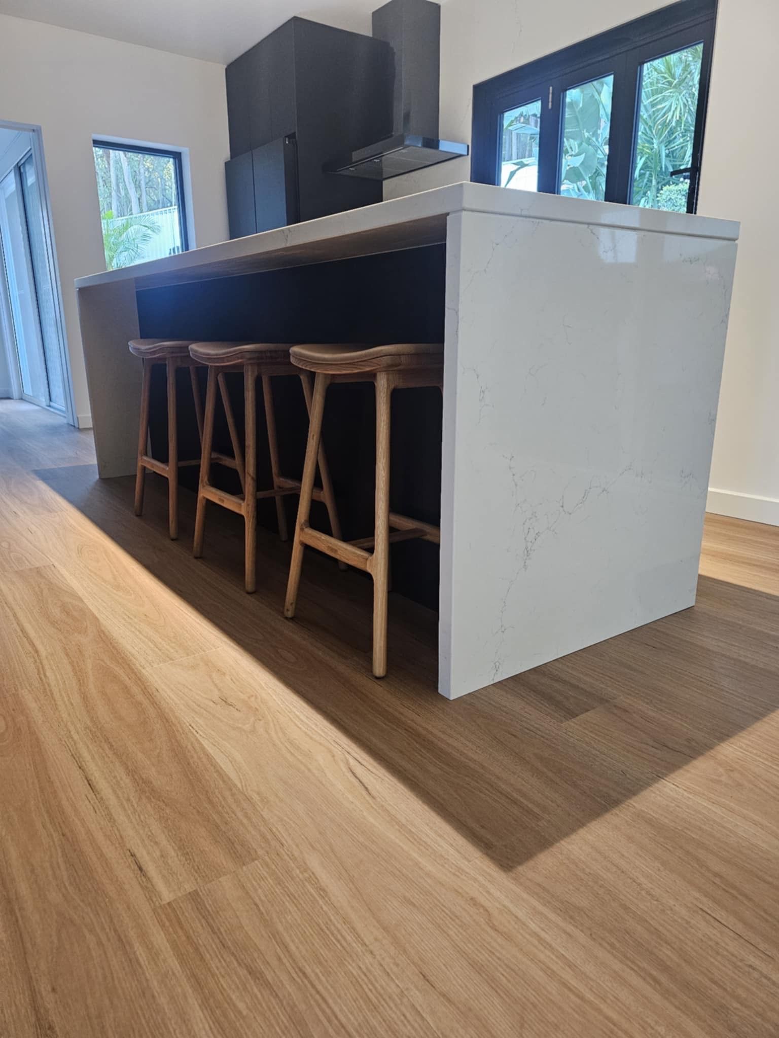A kitchen with a large island and wooden stools.