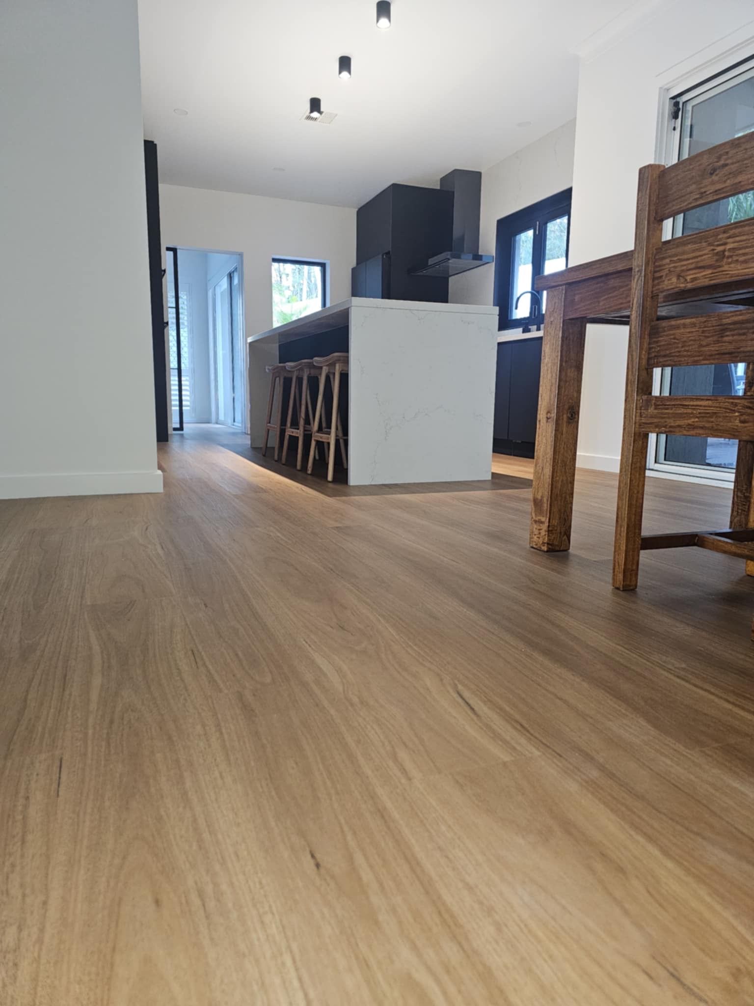 A kitchen with a wooden floor and a wooden table and chairs.