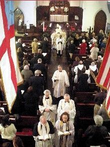 Congregation and clergy walking down the aisle during a church service, with American flags in the foreground