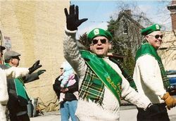 People in green St. Patrick’s Day outfits waving outdoors