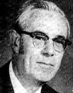 Black-and-white portrait of a man wearing glasses, looking slightly to the side.