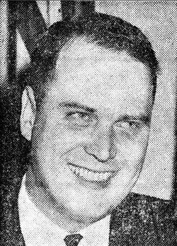 Black-and-white portrait of a smiling man in a suit and tie.