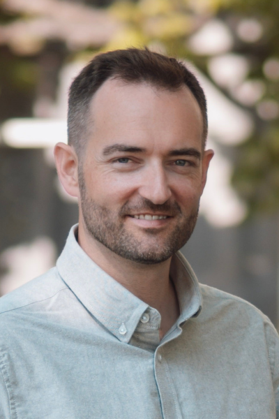 A man with a beard wearing a light blue shirt is smiling for the camera. Matt Baker at The HMO Platform.