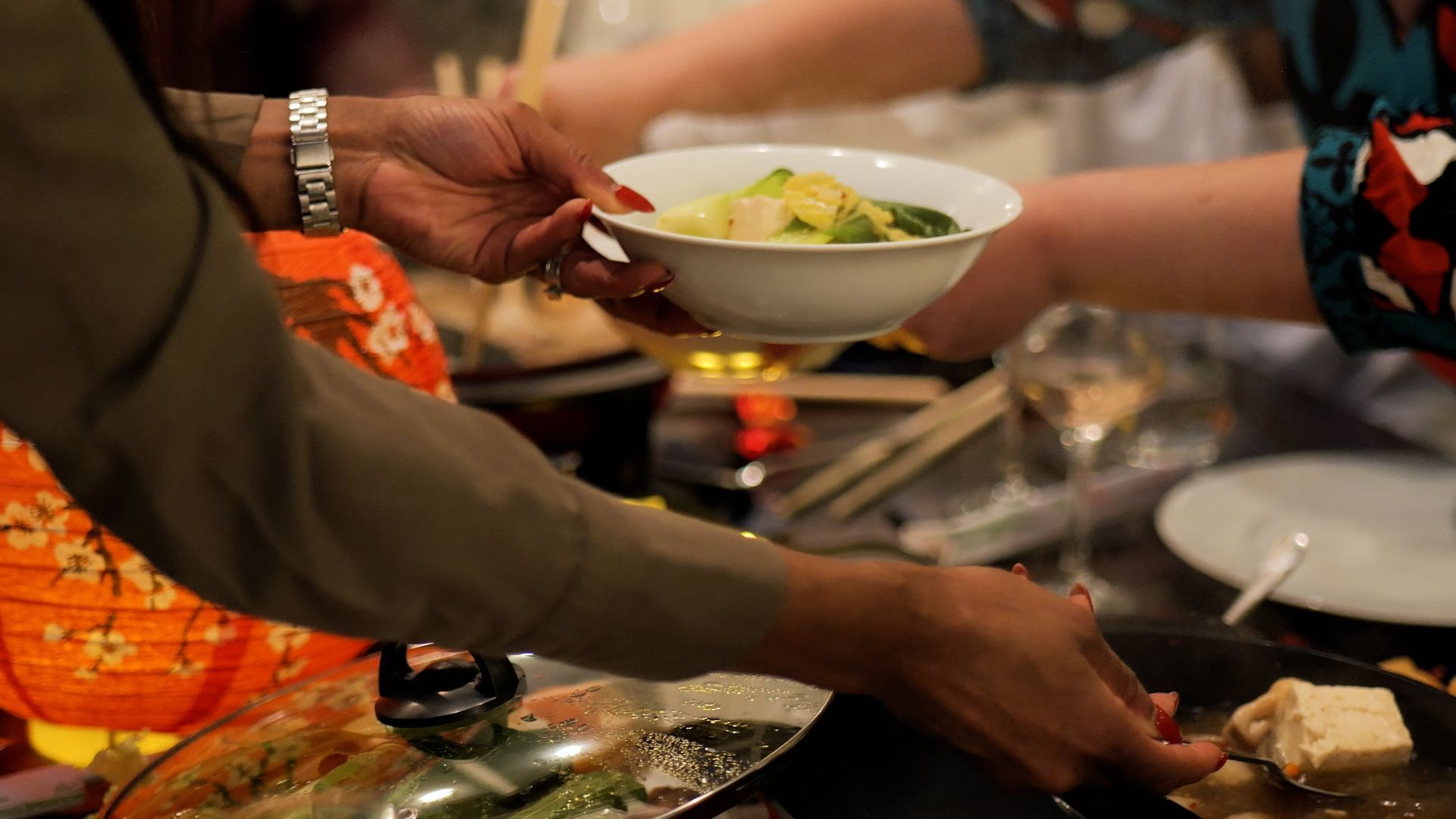 A woman is giving a bowl of food to another woman.