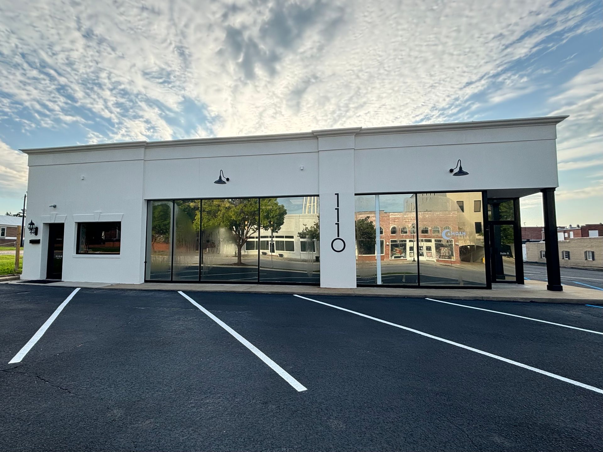 A white building with a lot of windows and a parking lot in front of it.