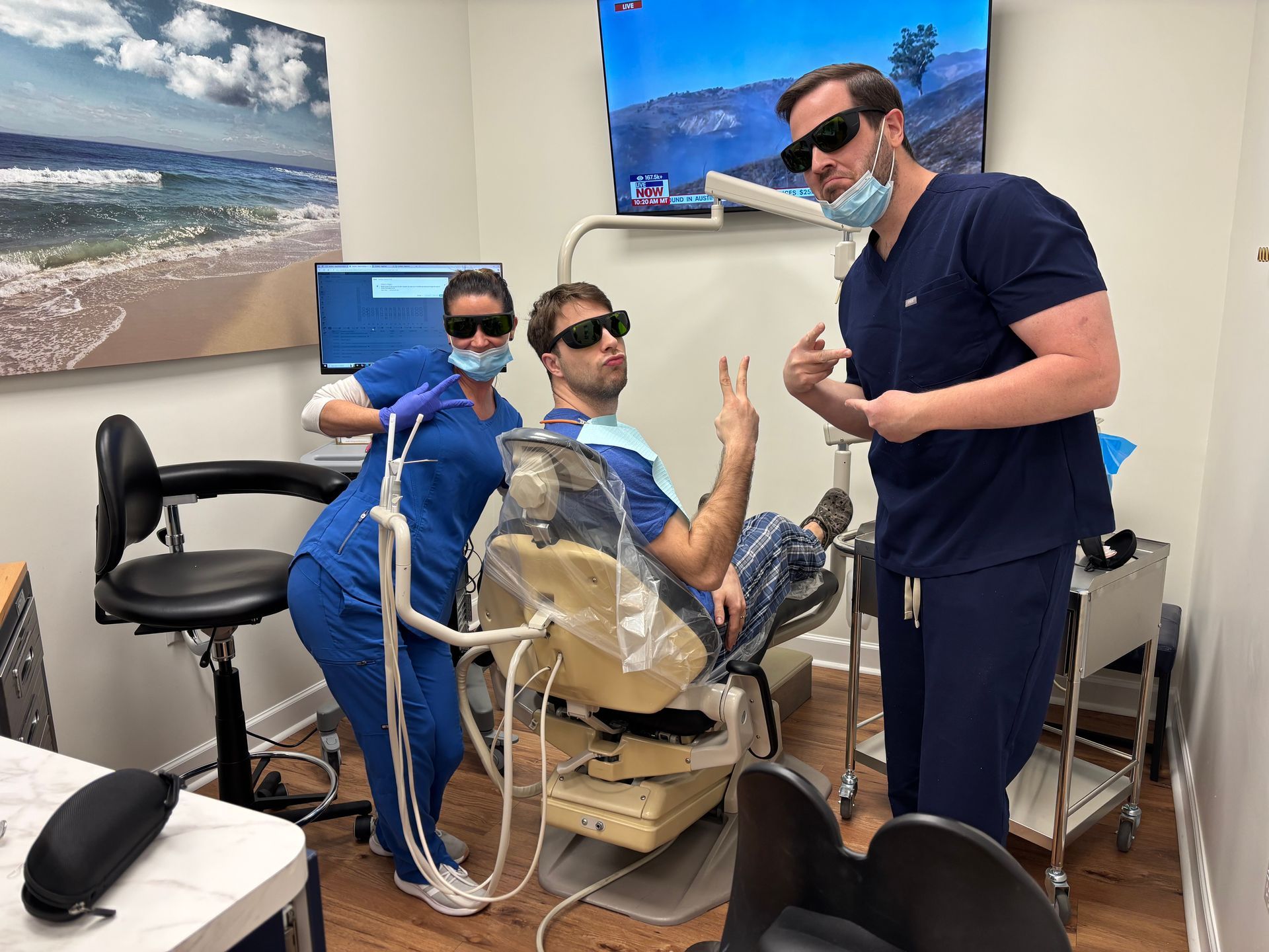 Three people in a dentist's office posing with sunglasses. One patient and two dental staff members.