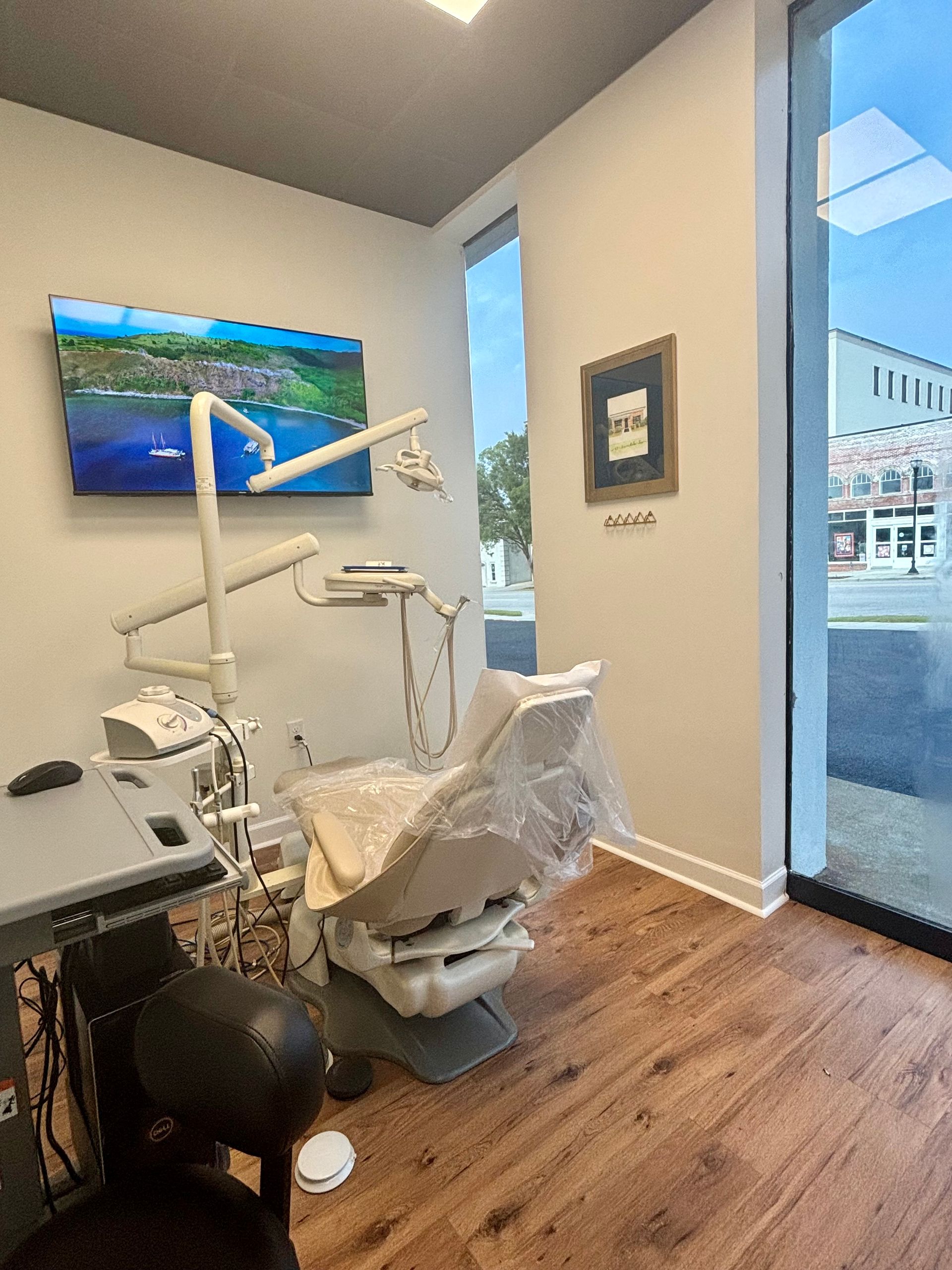 A dental office with a dental chair and a painting on the wall.