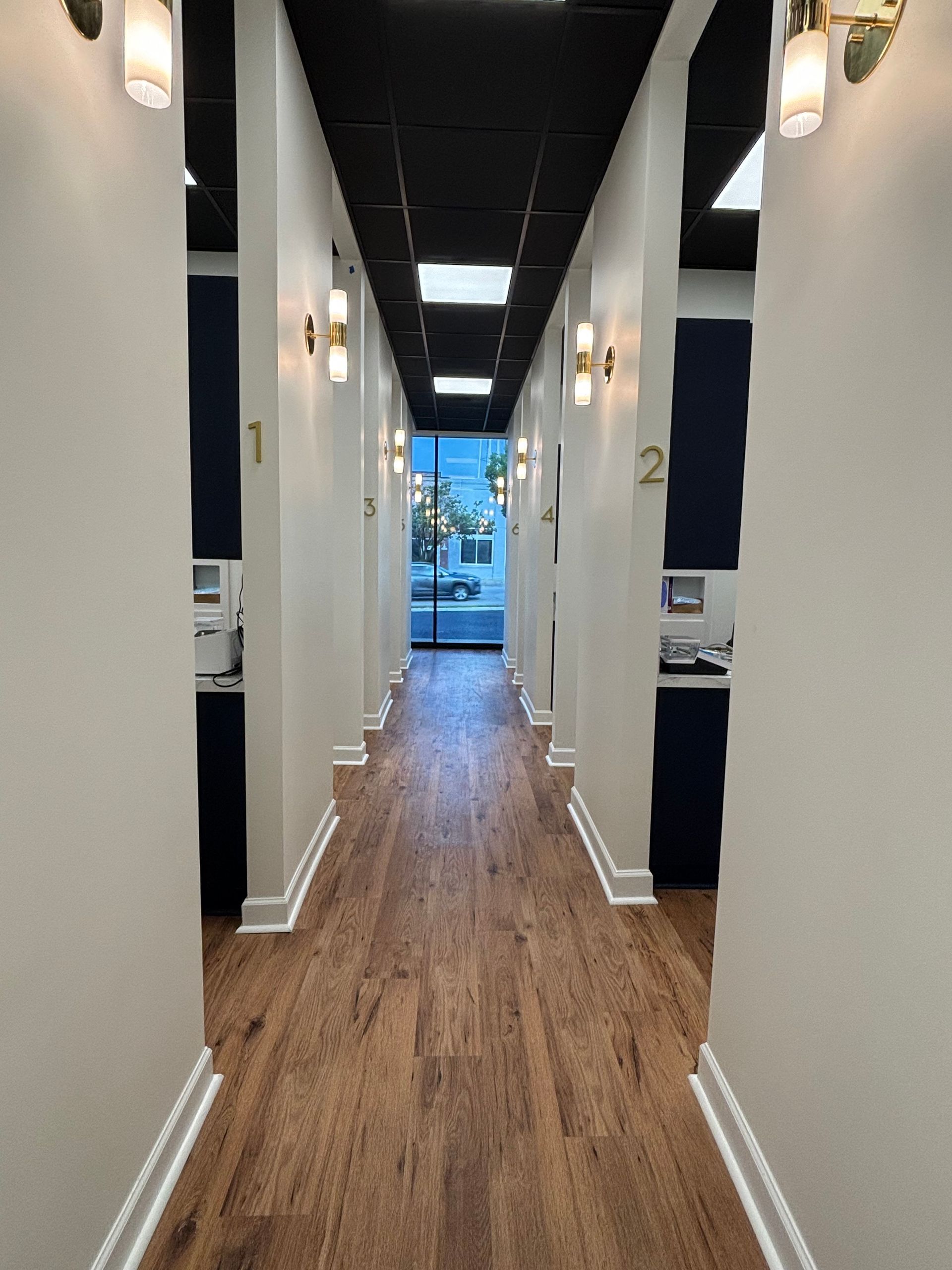 A long hallway with wooden floors and white walls in a dental office.