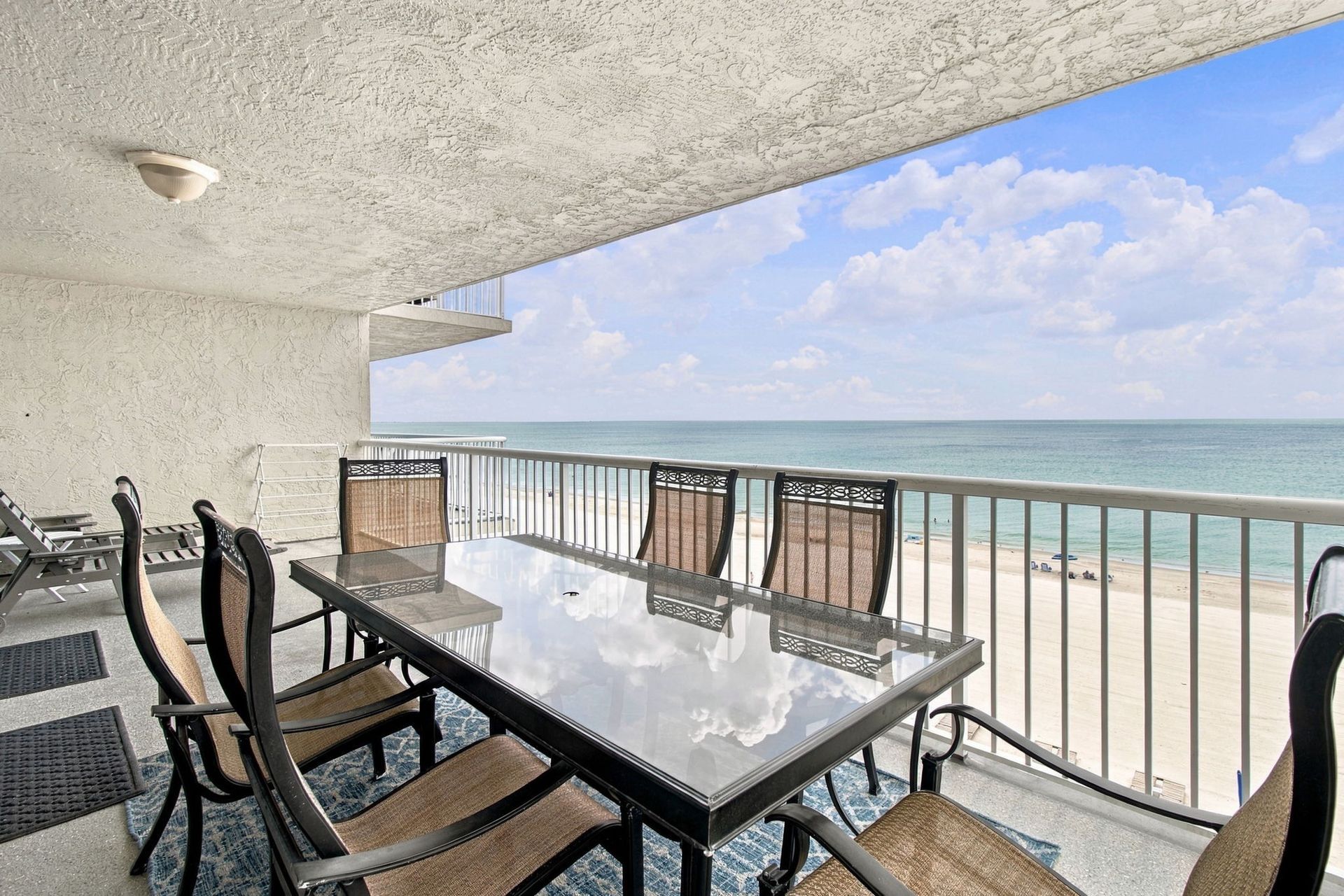 Furnished Gulf-front condo balcony with a dining table and chairs overlooking Madeira Beach and the water.
